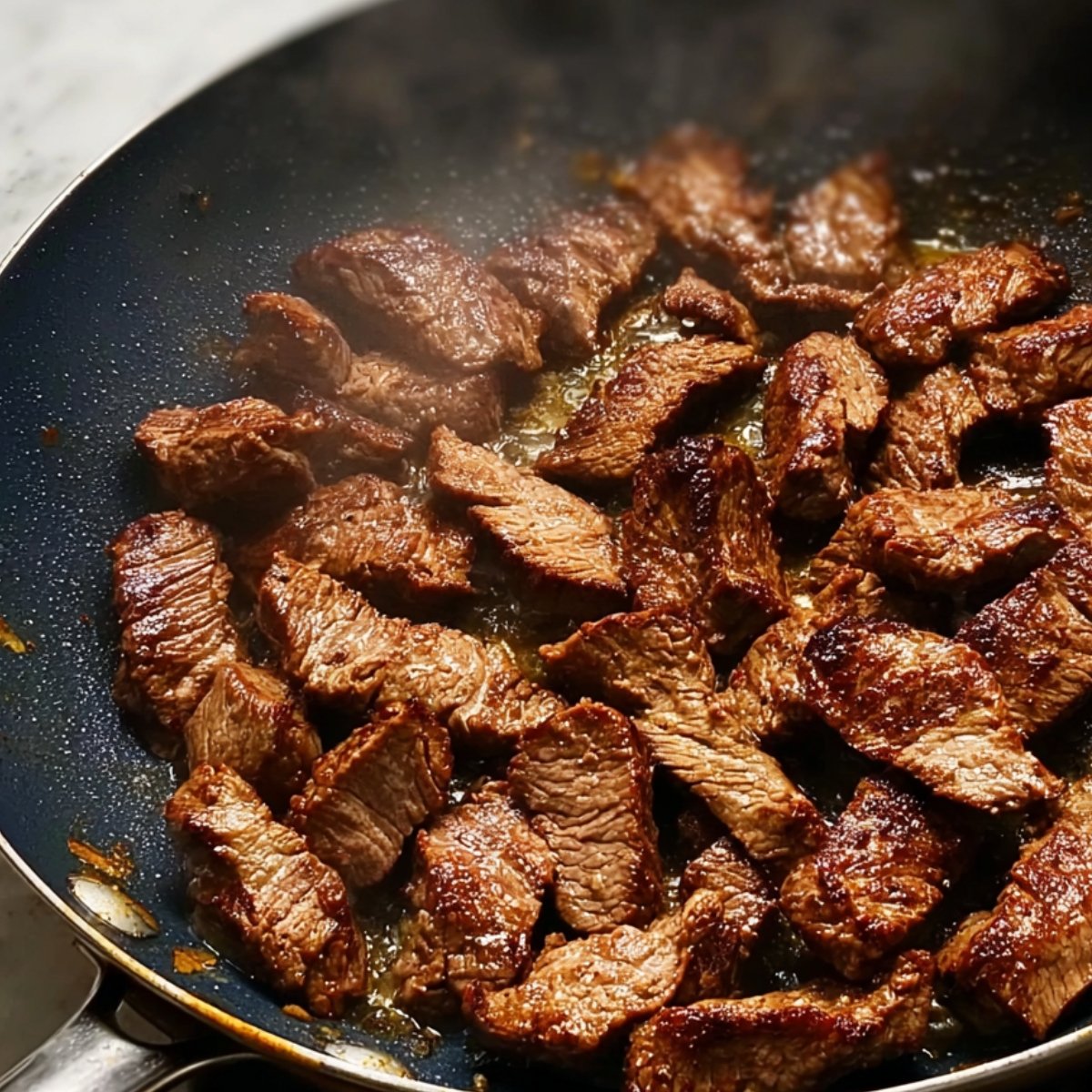 Perfectly browned beef strips sizzling in a pan, ready to be combined with other ingredients for a hearty dish.