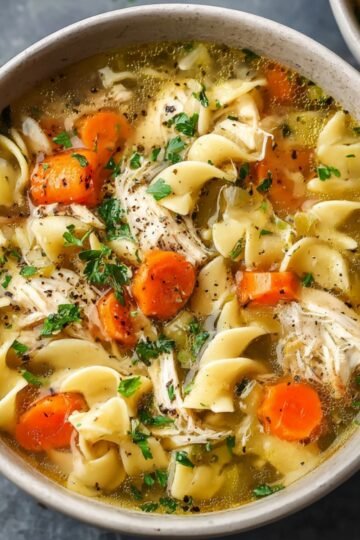 Chicken noodle soup with vegetables, noodles, and shredded chicken in a bowl.