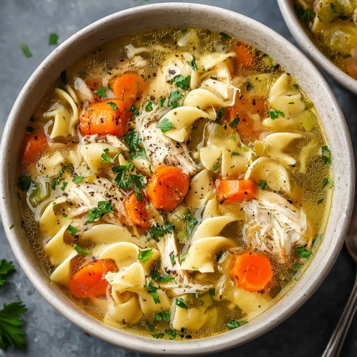 Chicken noodle soup with vegetables, noodles, and shredded chicken in a bowl.
