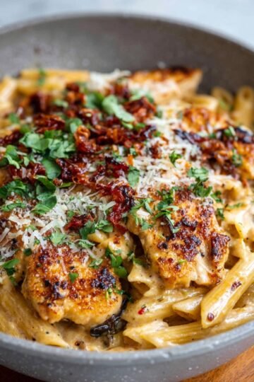 Creamy Marry Me Chicken Pasta with penne, crispy chicken, sun-dried tomatoes, parmesan, and fresh herbs in a serving bowl.