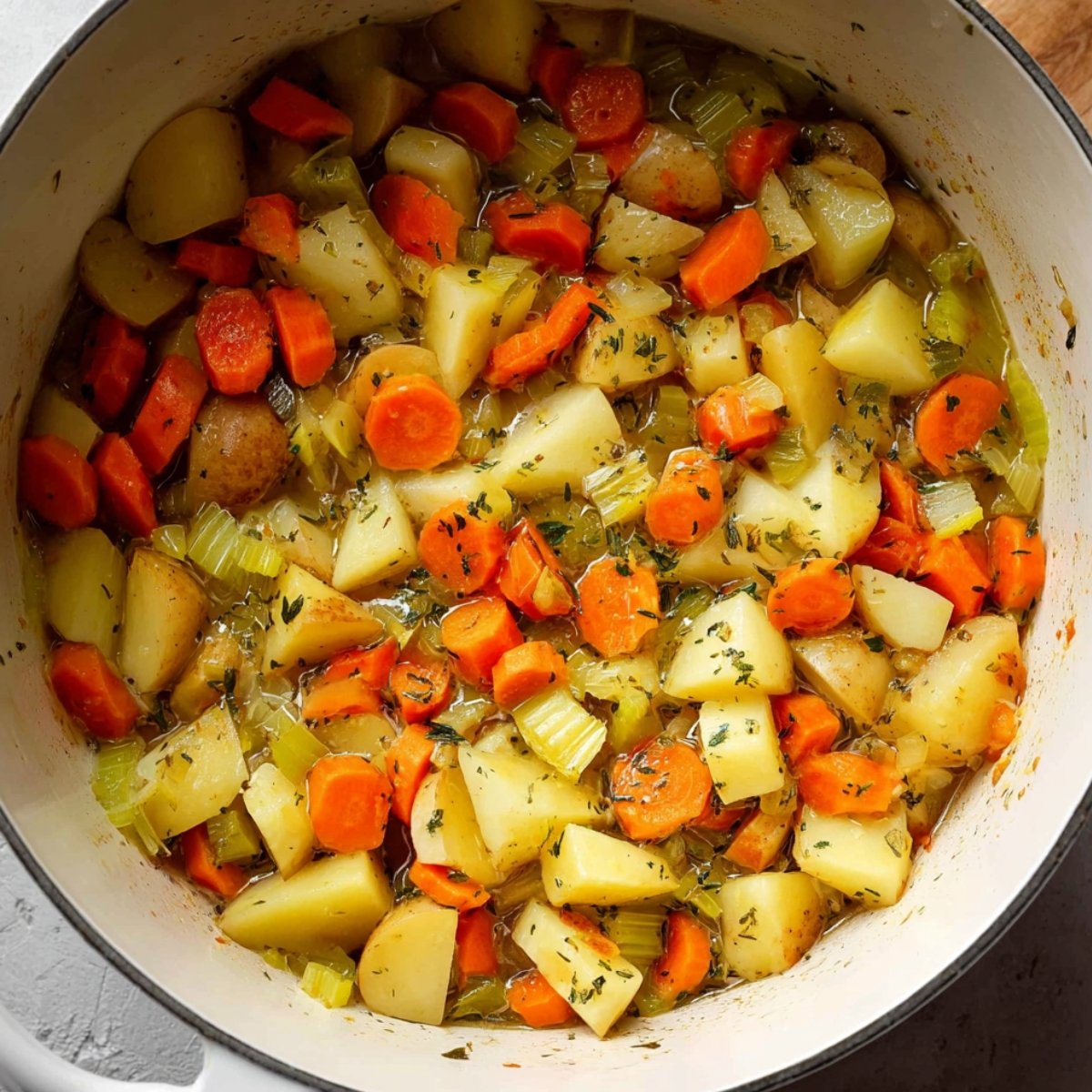 Chopped carrots and celery added to a pot with potatoes for a creamy vegetable soup.