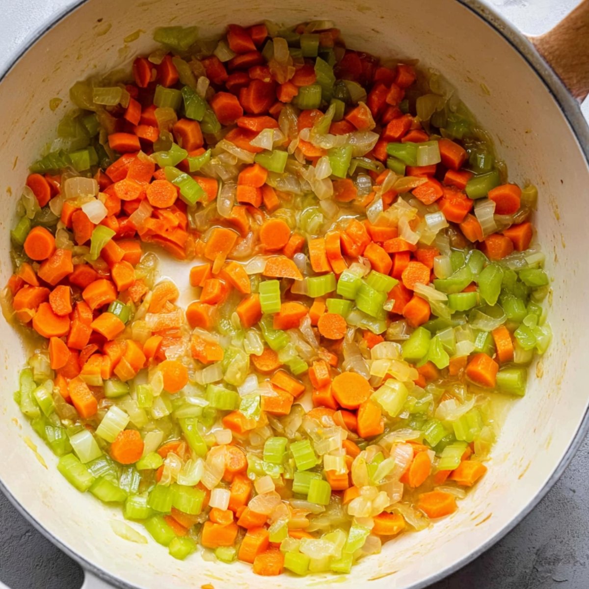 Sautéed onions, carrots, and celery in a large pot, preparing for vegetable soup.